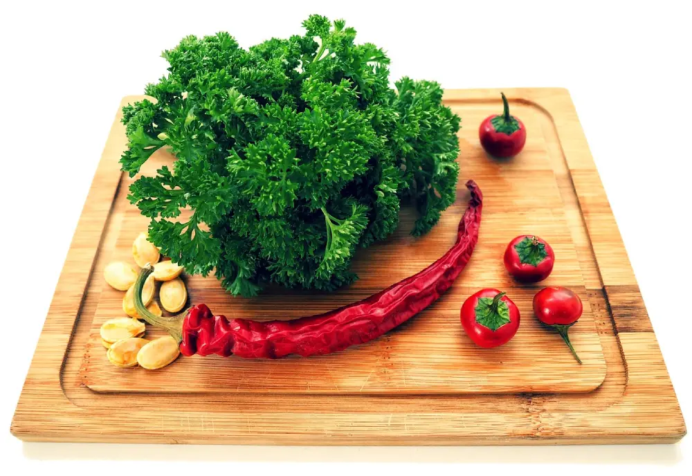 Bouquet de persil frisé frais sur planche à découper en bambou avec piments rouges et épices, ingrédients pour cuisine aromatique