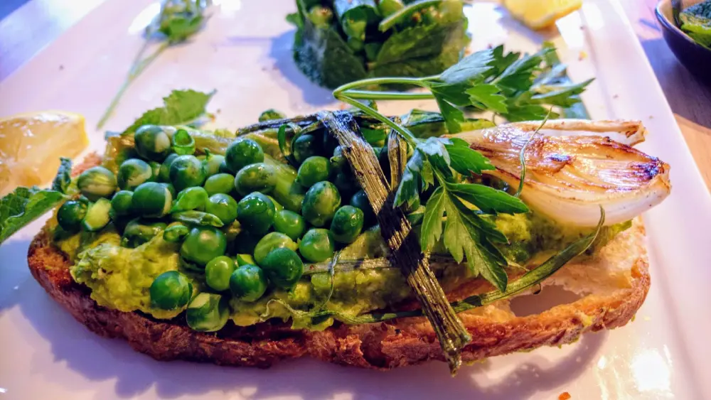 Tartine de petits pois frais écrasés avec oignon caramélisé et persil, repas gourmet végétarien riche en protéines, culture potagère bio