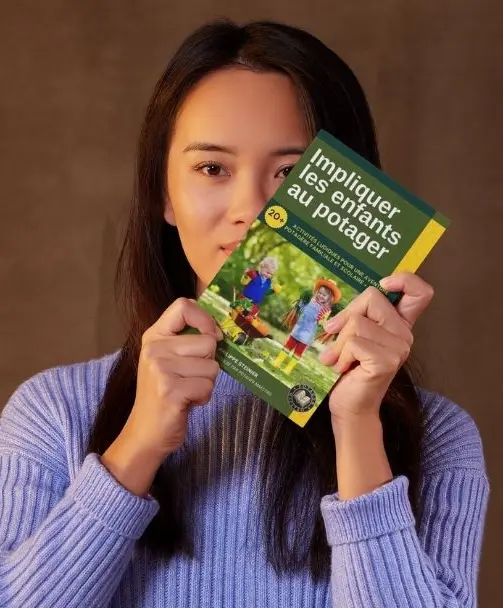 Jeune fille présentant entre ses mains le livre impliquer les enfants au potager