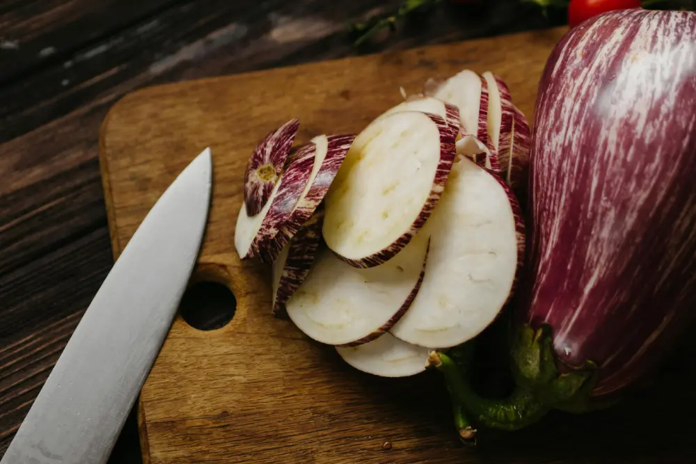 Aubergines violettes et blanches tranchées sur planche bois - préparation cuisine légumes frais