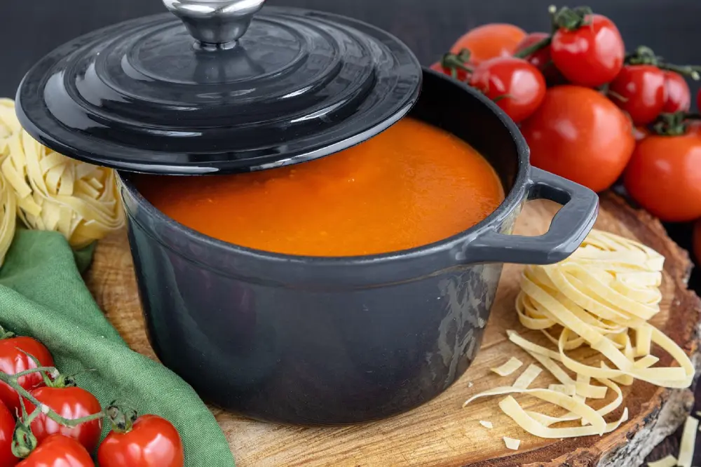 Sauce tomate maison dans casserole noire avec pâtes fraîches et tomates culture potager
