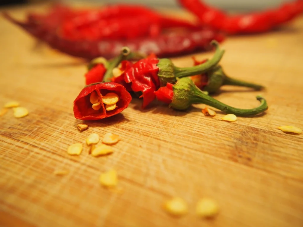 Piments rouges tranchés sur planche bois avec graines - Préparation et conservation des piments