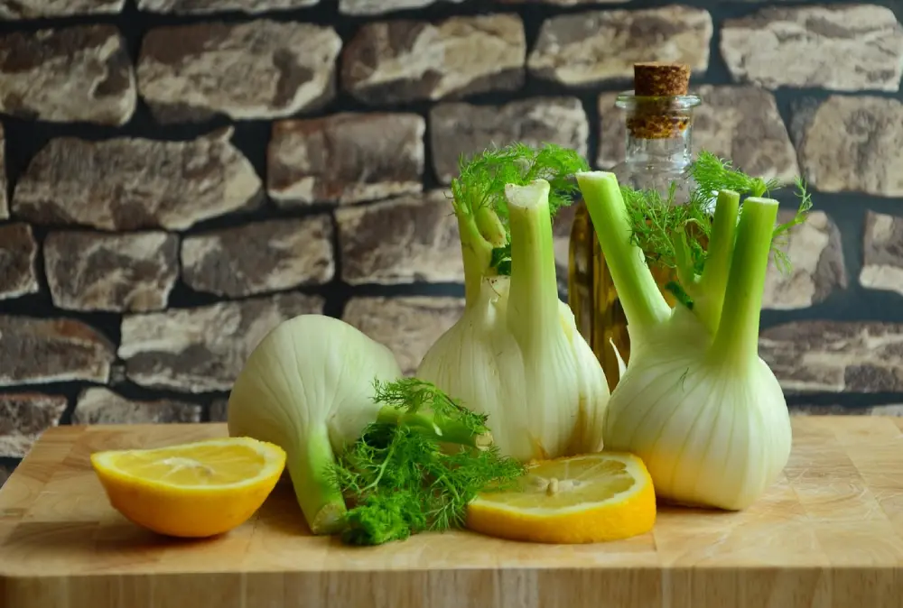 Fenouils frais planche bois orange huile olive - préparation culinaire ingrédients