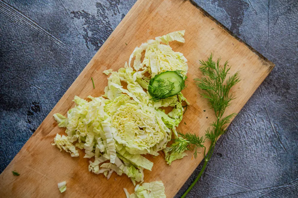 Chou de Milan découpé sur planche bois avec aneth frais - Préparation culinaire